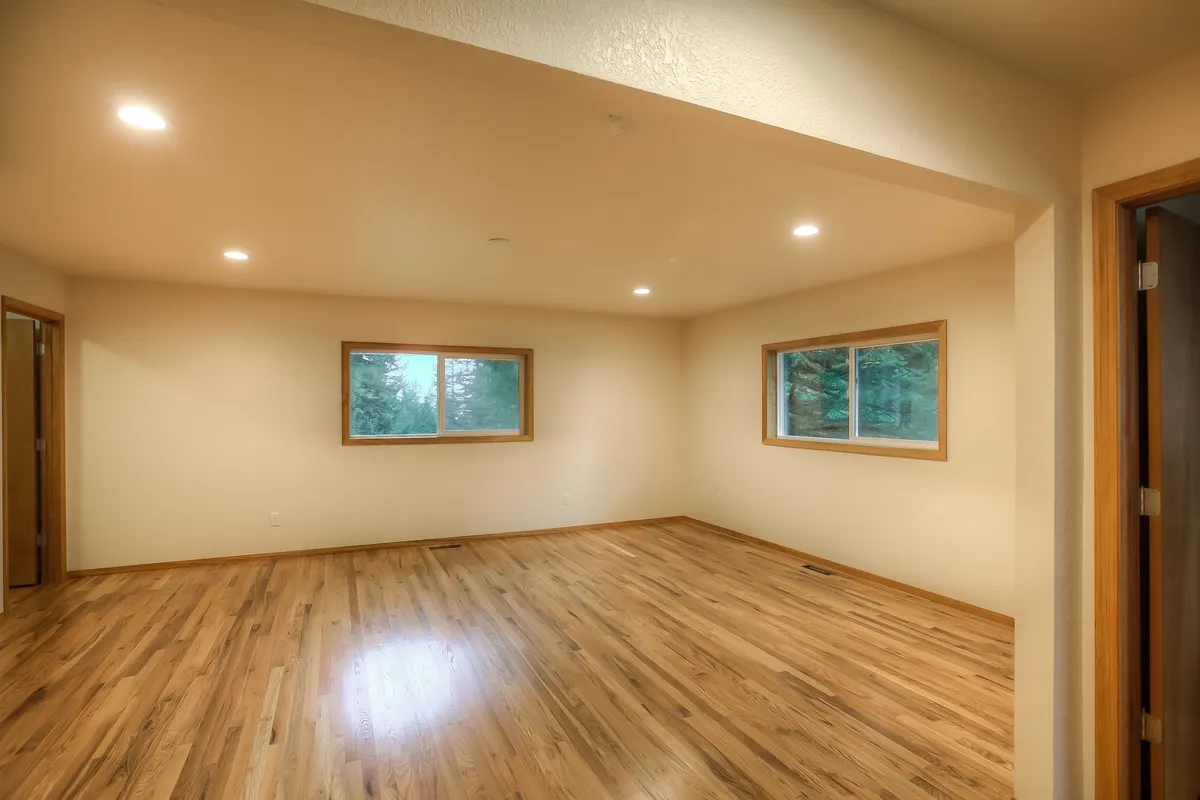 An empty new room with wood-look flooring and two windows