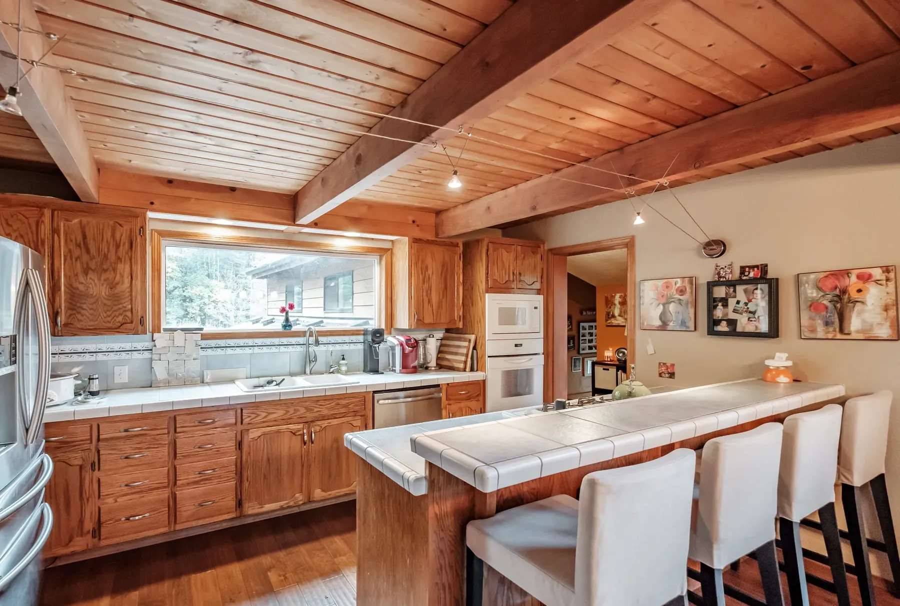 The Corvallis kitchen before: oak cabinets and a tiled peninsula under the wood ceiling