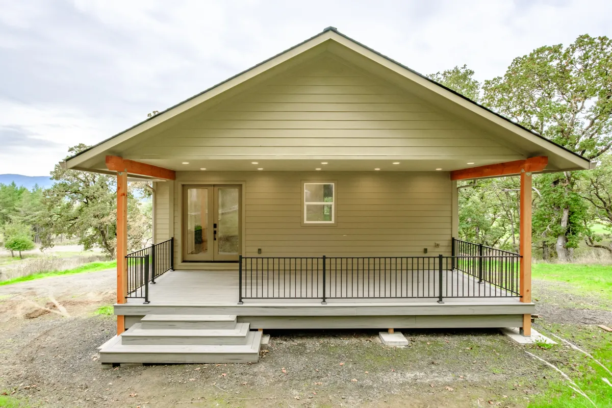 A new covered porch on a cream house with cedar posts, black railing and wide steps