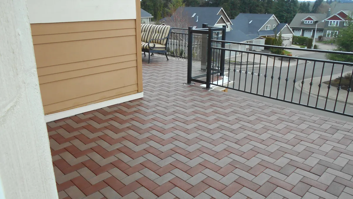 A paver patio with a herringbone border and black aluminum railing