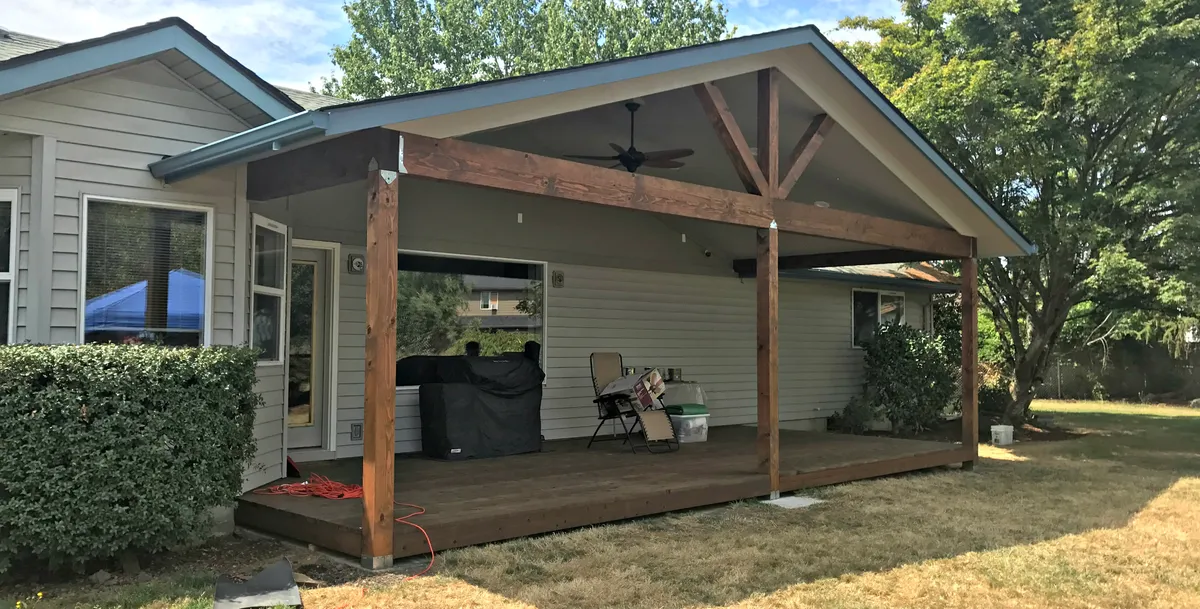 A gabled covered patio with outdoor furniture beside the house