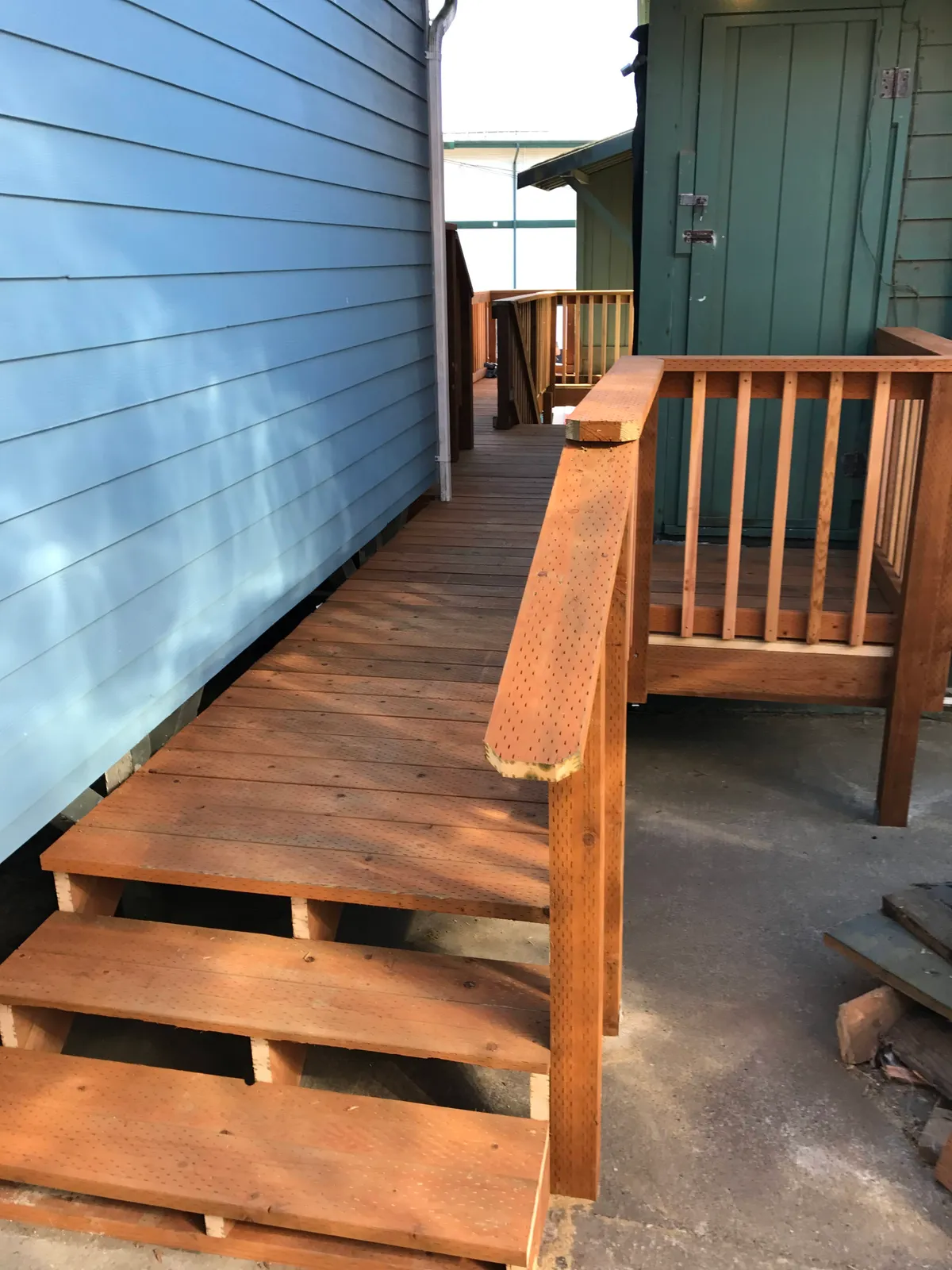 Cedar stairs and railing at the side of a blue house