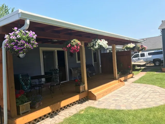 A covered porch with hanging flower baskets over a paver patio