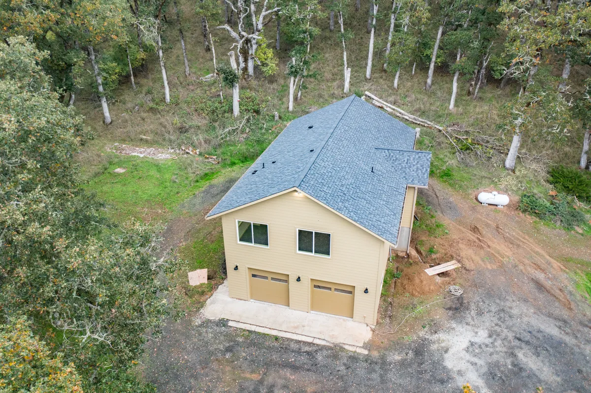 The rebuilt home and two-car garage among the oaks, from above