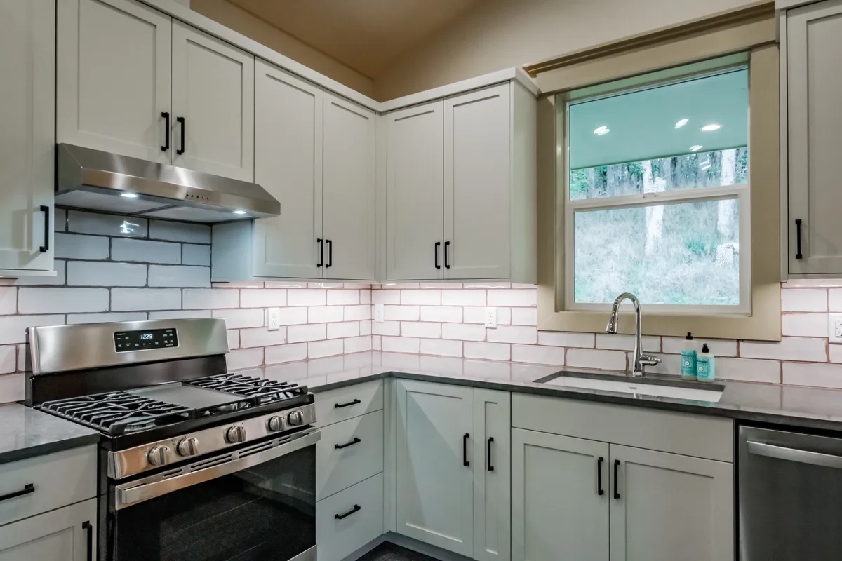Kitchen with sage cabinets, subway tile and pull-out storage