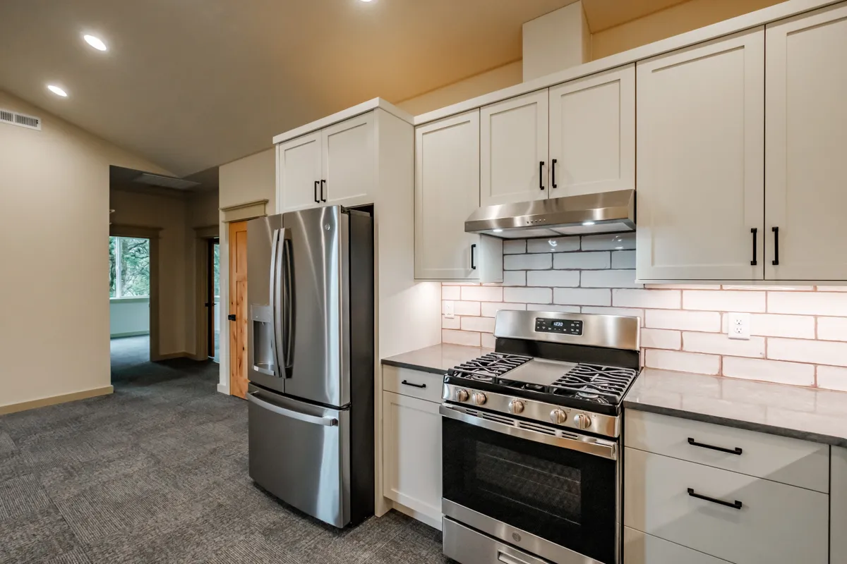Kitchen with sage cabinets, subway tile and pull-out storage
