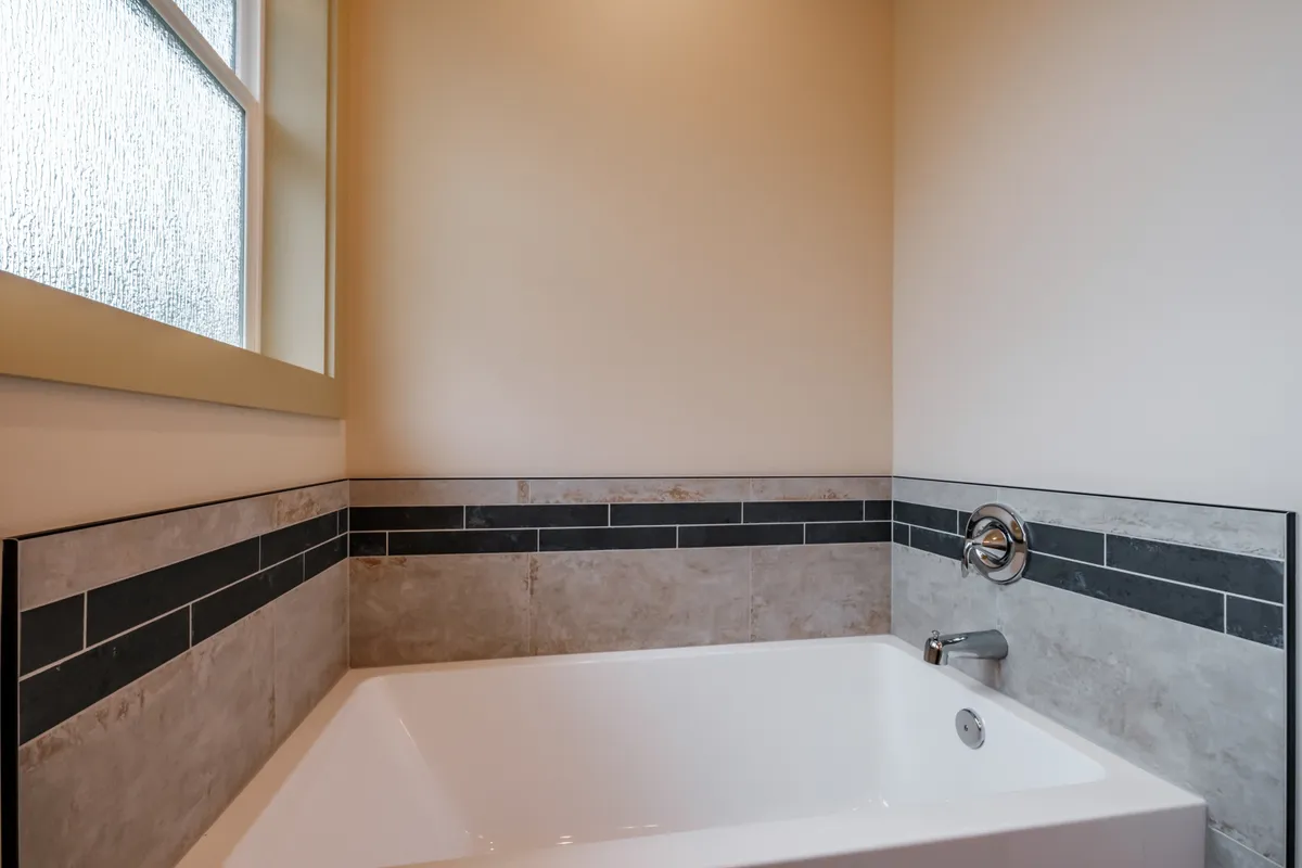Bathrooms with tiled tub surrounds and dark counters