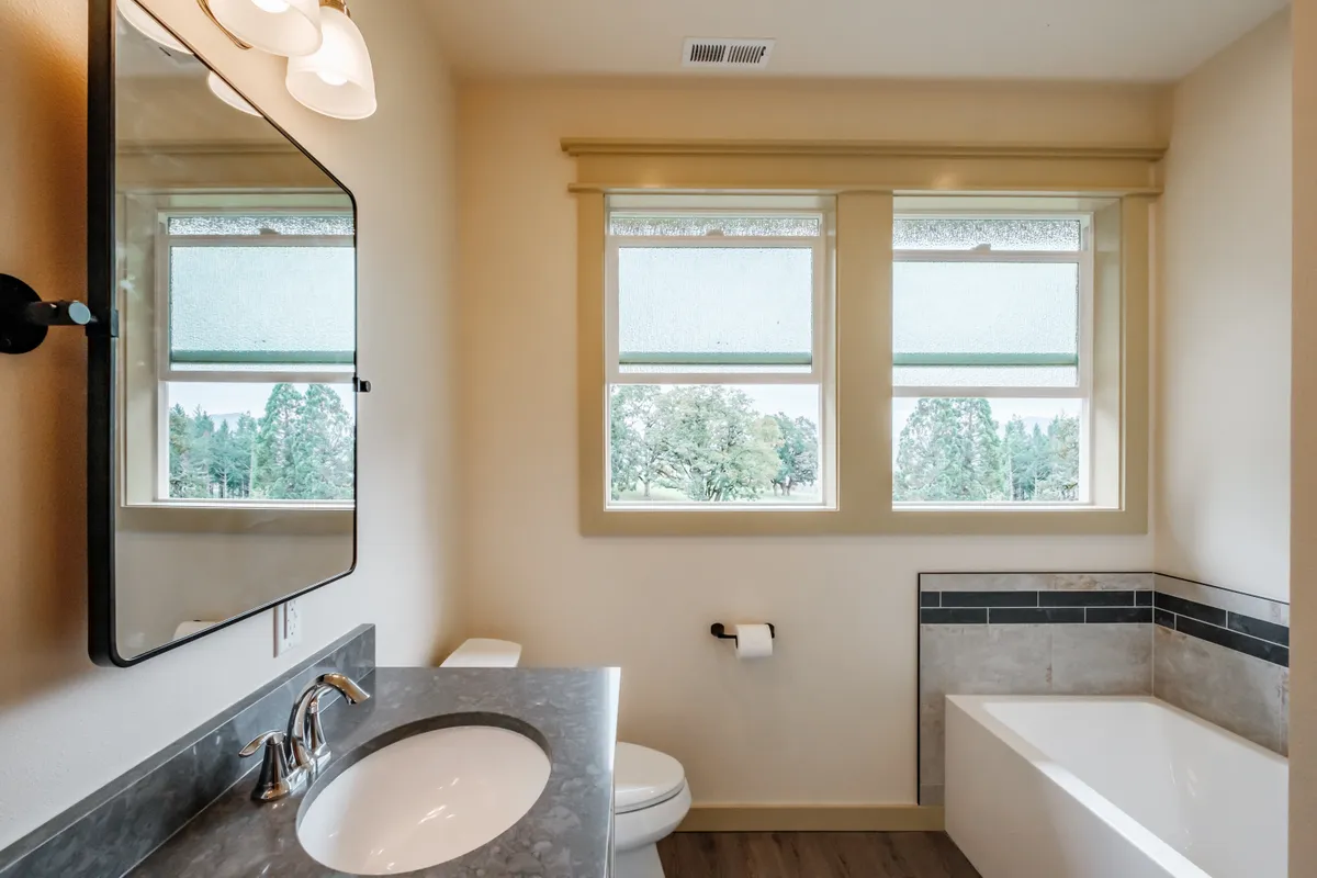Bathrooms with tiled tub surrounds and dark counters