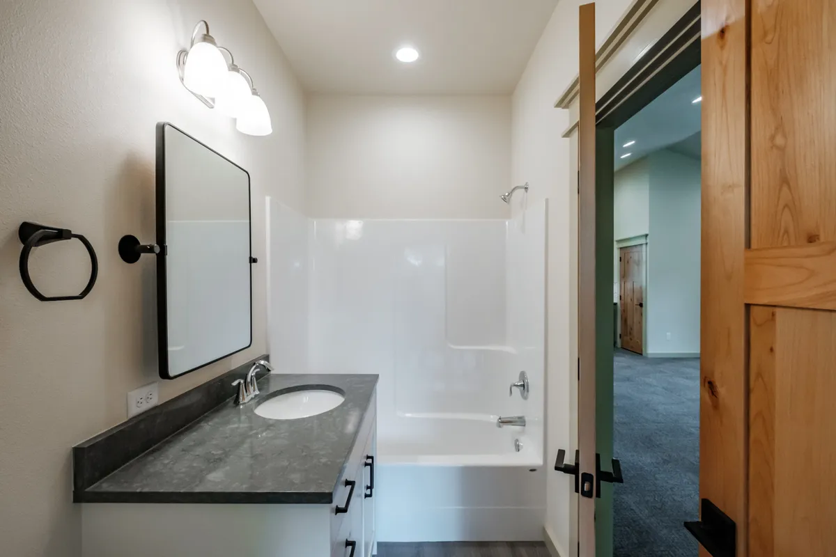 Bathrooms with tiled tub surrounds and dark counters