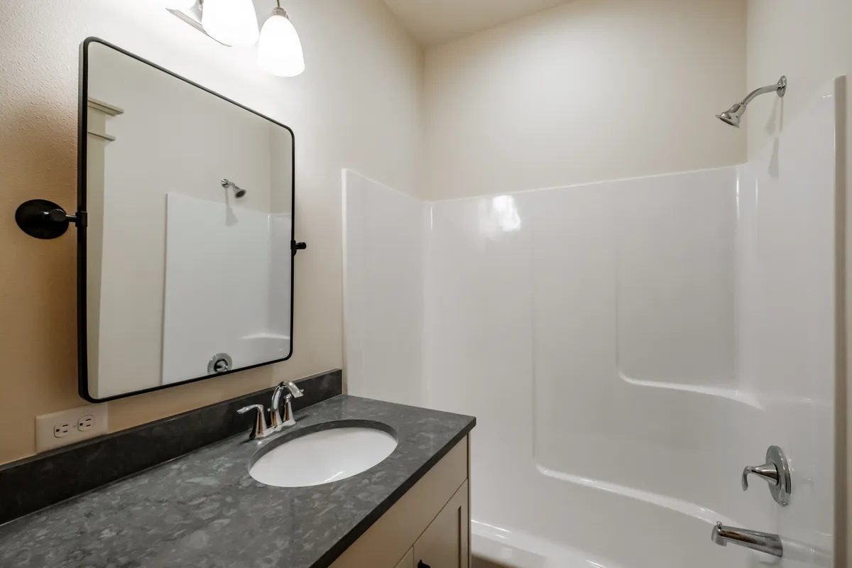 Bathrooms with tiled tub surrounds and dark counters