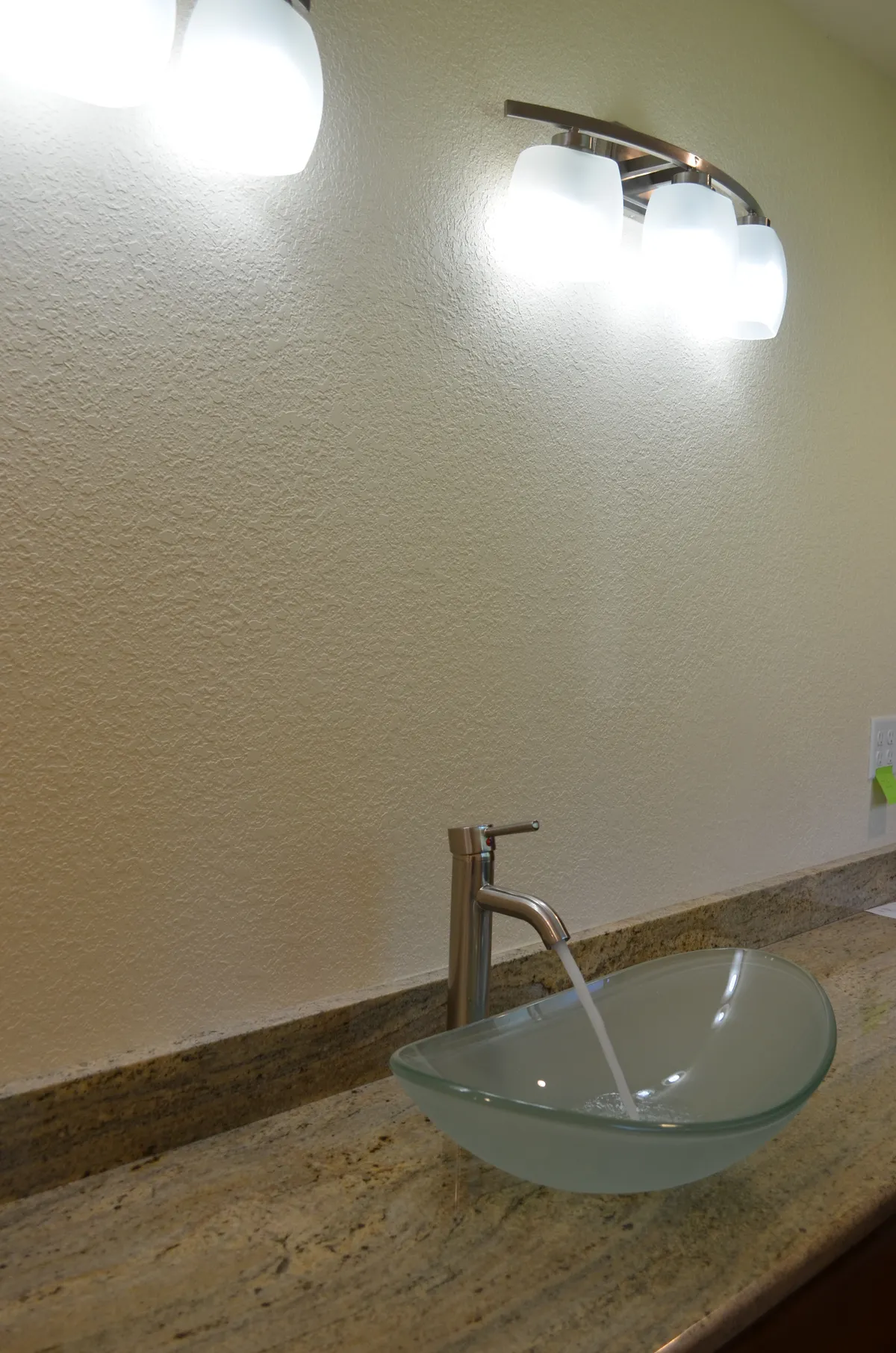A glass vessel sink on a granite counter