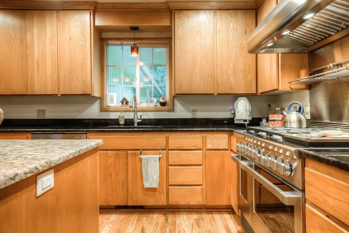 The refreshed kitchen with wood cabinets, granite and a stainless hood