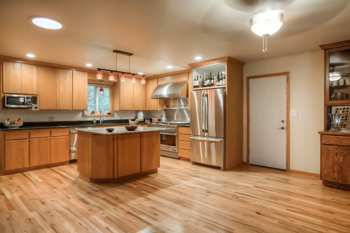 A warm wood kitchen with an island, granite counters and new hardwood floors