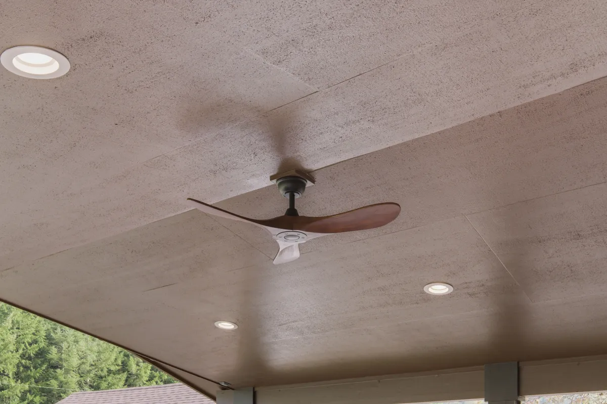 The covered deck with recessed lights and a ceiling fan