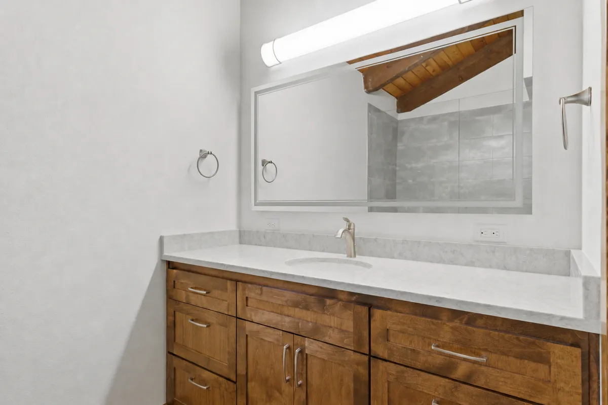 Bathroom vanity and tiled walk-in shower with a glass door