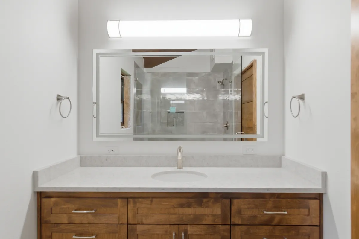 Bathroom vanity with a lighted mirror and an alder door