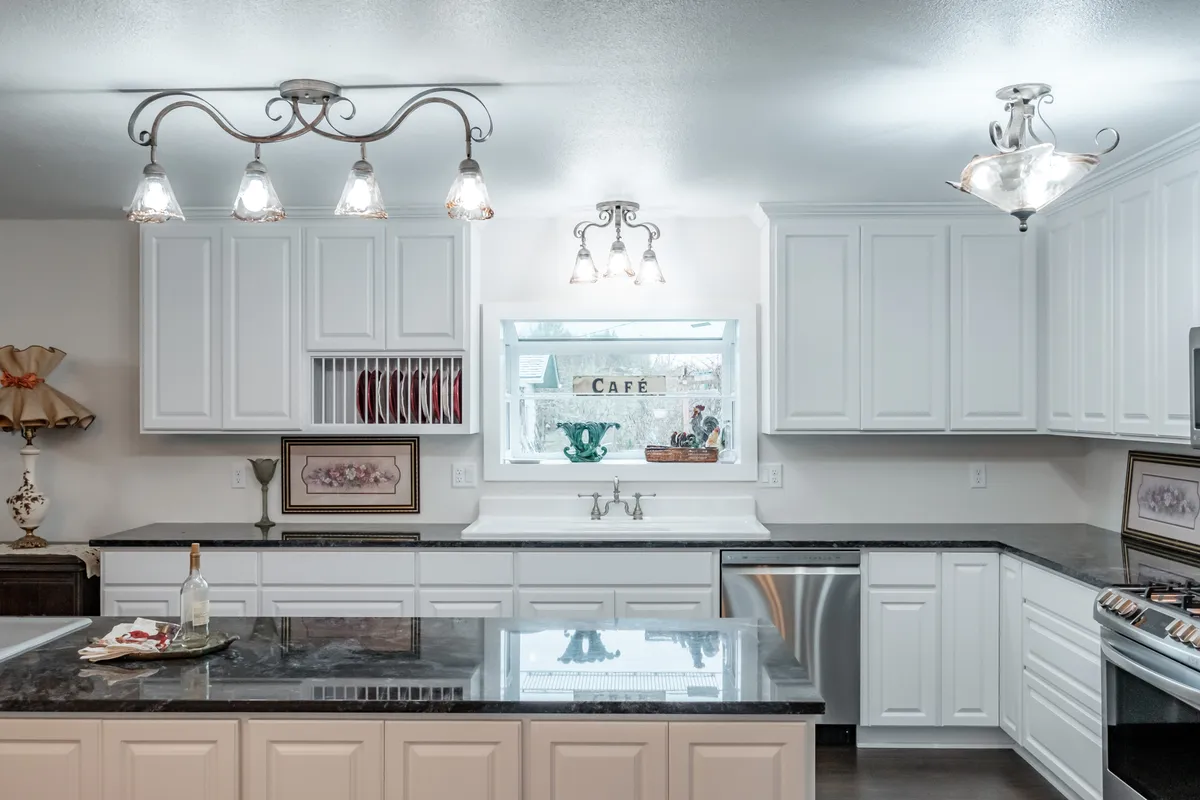 The Lebanon kitchen after: white cabinets, black granite counters and a café window